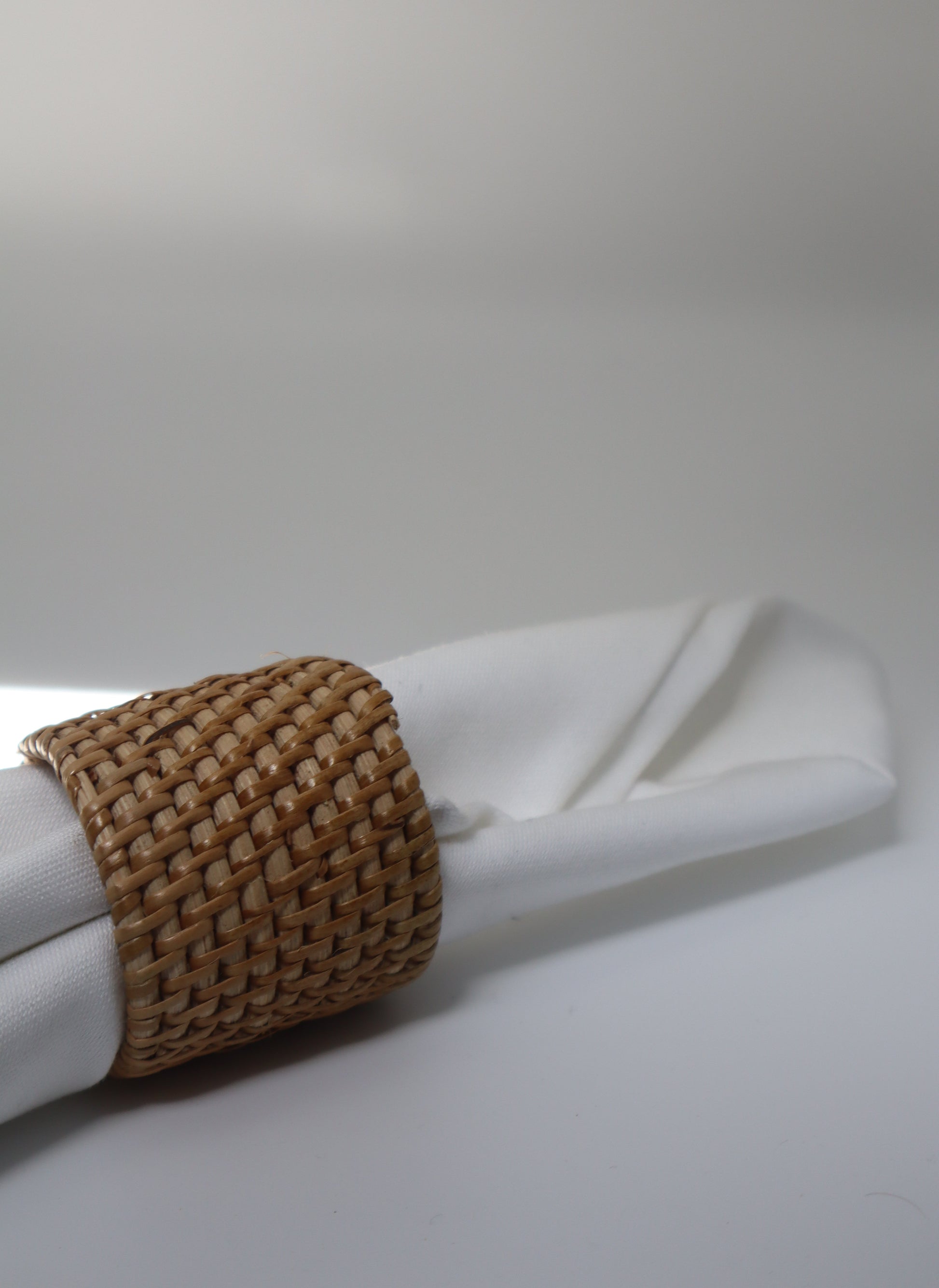 Napkin ring with woven design on a white napkin against a plain background